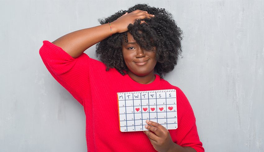 a woman holding calendar marked with her monthly cycle